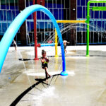 kid plays in large sprinkler